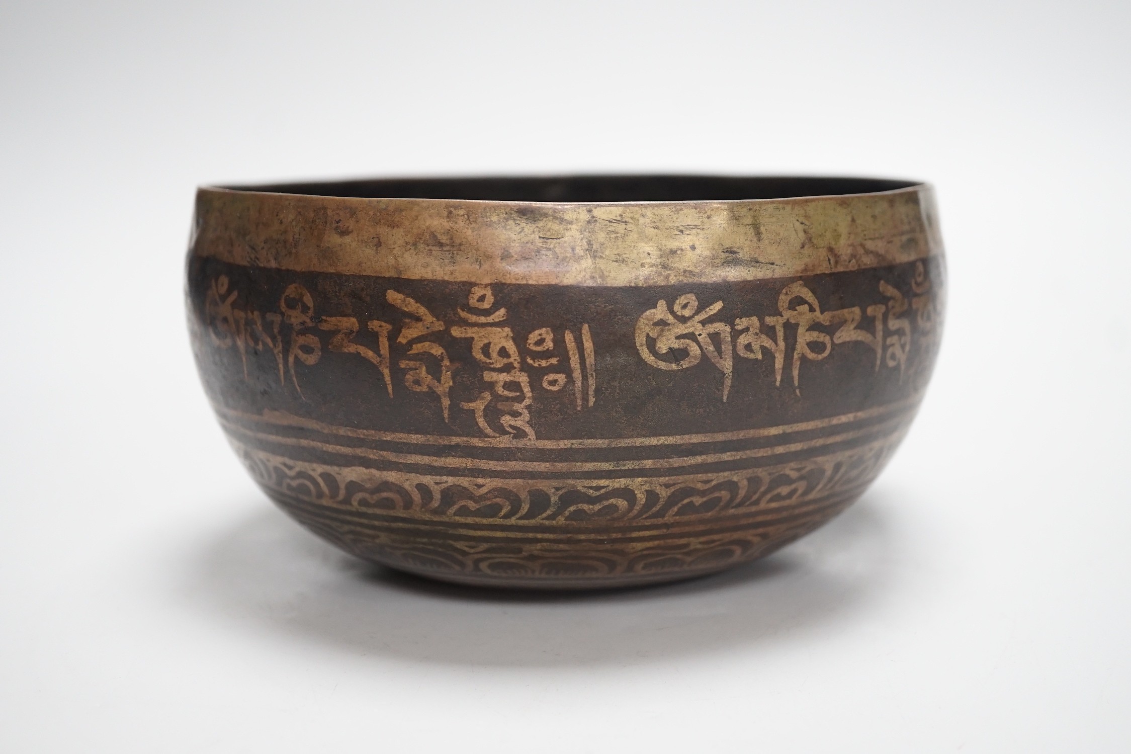 A bronze Nepalese temple bowl decorated with script, 18cm diameter